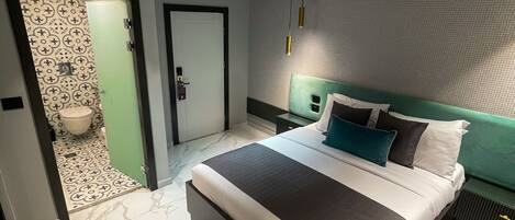 Quarto moderno com uma cama grande, cabeceira verde e piso de mármore.