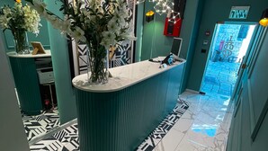 Un espace d’accueil moderne avec un mur d’accent de couleur turquoise, un sol en marbre et un luminaire décoratif.