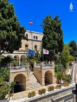 Um edifício histórico com janelas em arco e uma escadaria de pedra que leva a uma ponte.