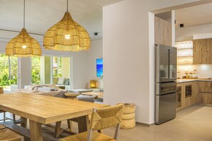 Una cocina moderna con una gran mesa de madera, dos lámparas de mimbre colgantes y armarios empotrados de madera.