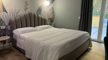 Una camera da letto con un letto, un tavolino rotondo e una parete decorata con un motivo a foglia tropicale.