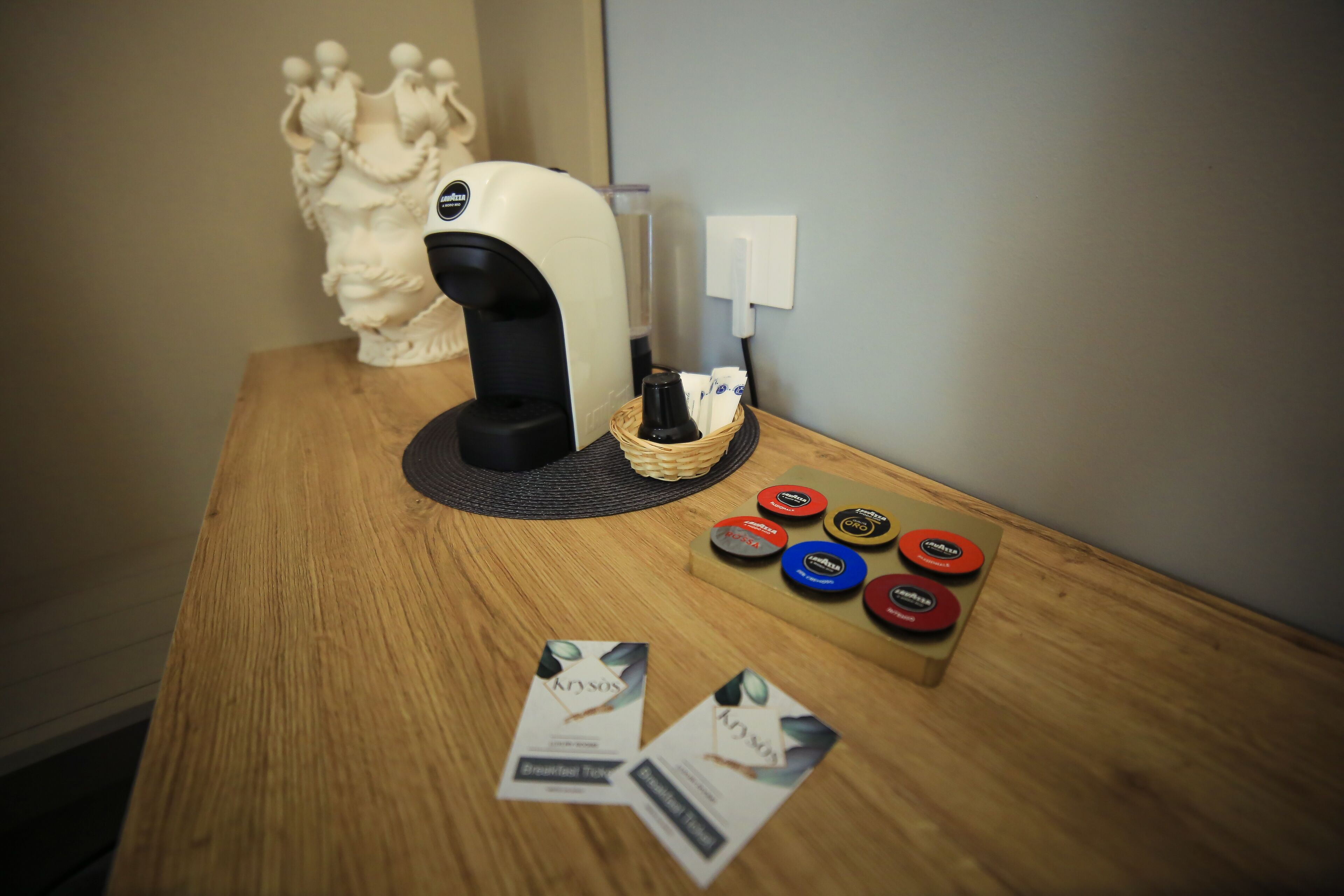 A wooden table with a coffee machine, a decorative vase, and some brochures.
