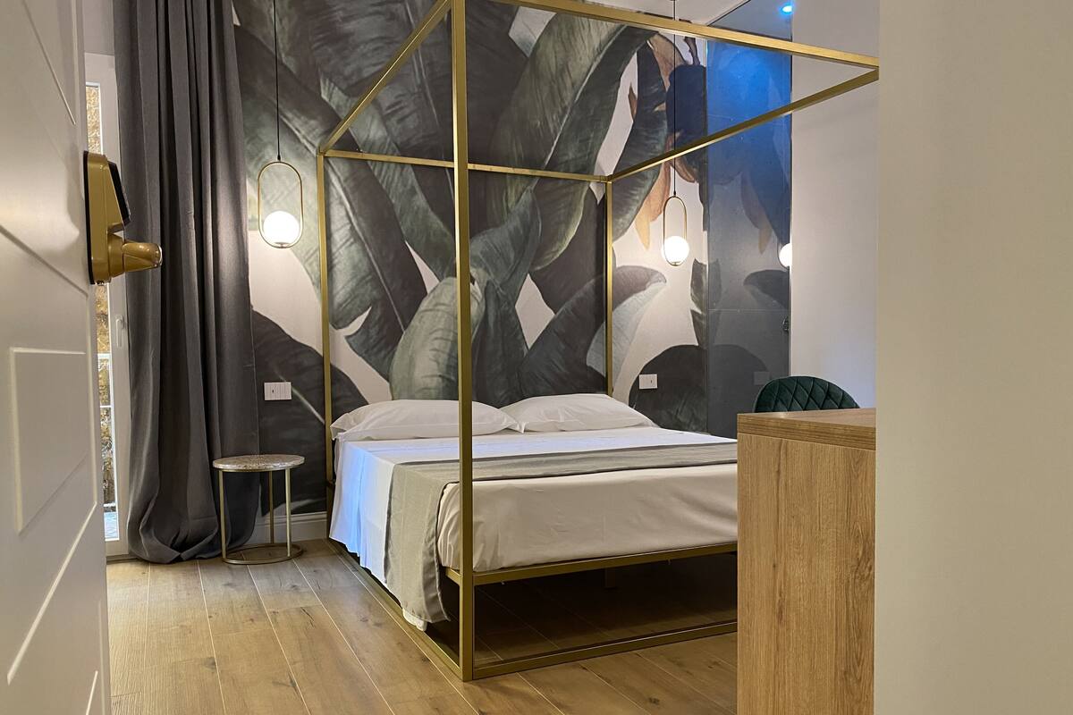 A bedroom with a four-poster bed, a small side table, and a wooden nightstand.