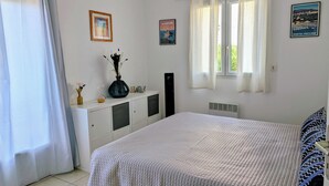 A bedroom with a bed, a dresser, a radiator, and a window with curtains. - T2 sea view apartment (Tizzano)