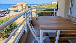 A balcony with a wooden table and benches overlooking a parking area and the sea. - T2 sea view apartment (Tizzano)