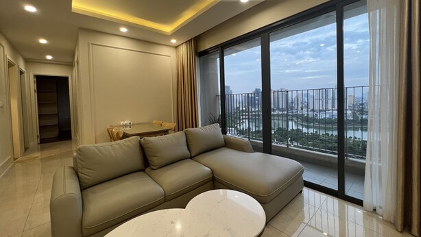 Ein modernes Wohnzimmer mit einem Ecksofa, einem kleinen runden Tisch und einem großen Fenster mit Blick auf die Stadt.