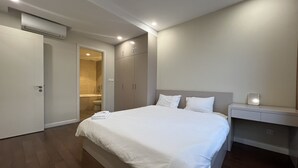 Ein Schlafzimmer mit einem großen Bett, einem Nachttisch, einem Kleiderschrank und einer Klimaanlage.