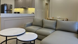 Eine moderne Küche mit grauen Schränken, einem Einbauofen und einem Essbereich mit grauem Sofa und zwei runden Tischen.