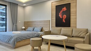 Ein modernes Hotelzimmer mit einem Bett, einer Couch, einem kleinen Tisch und einem großen Gemälde an der Wand.