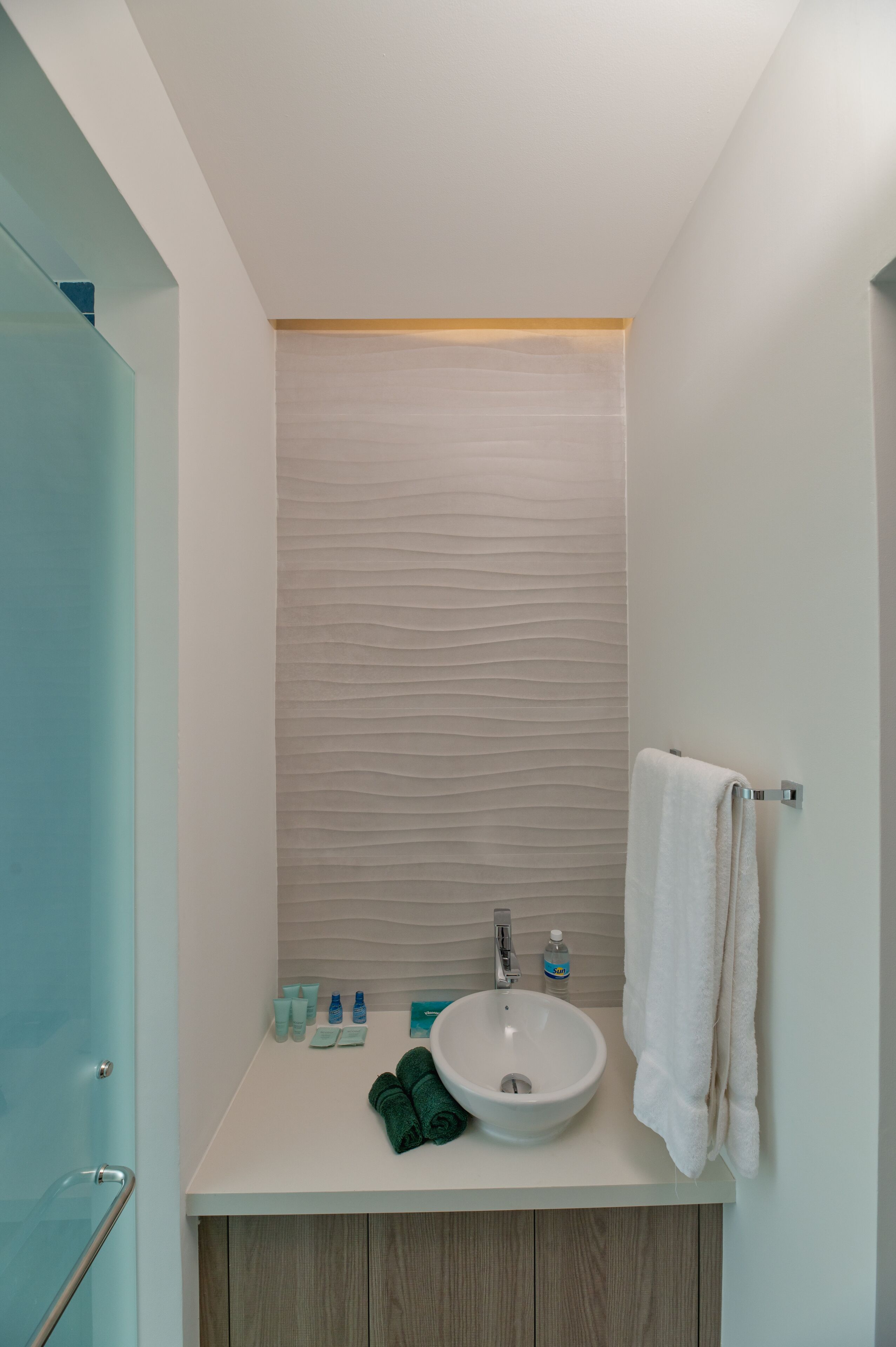 A modern bathroom with a white sink, a towel rack, and a glass shower enclosure.