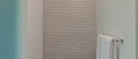 A modern bathroom with a white sink, a towel rack, and a glass shower enclosure.