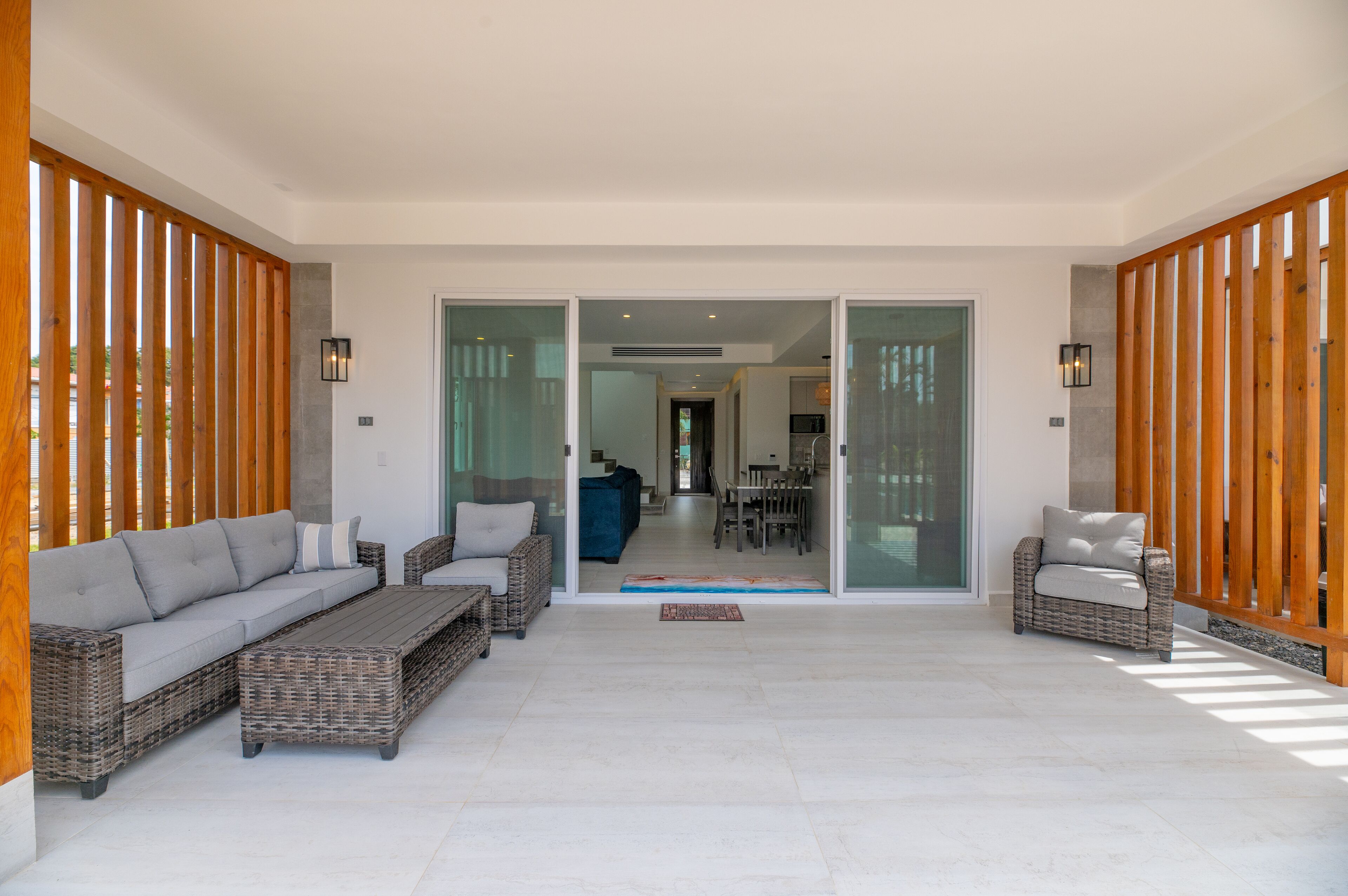 A spacious living area with a grey sofa, wicker chairs, and a coffee table.