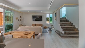 Un salon moderne comprenant un canapé, une table à manger et un escalier menant à un niveau supérieur.