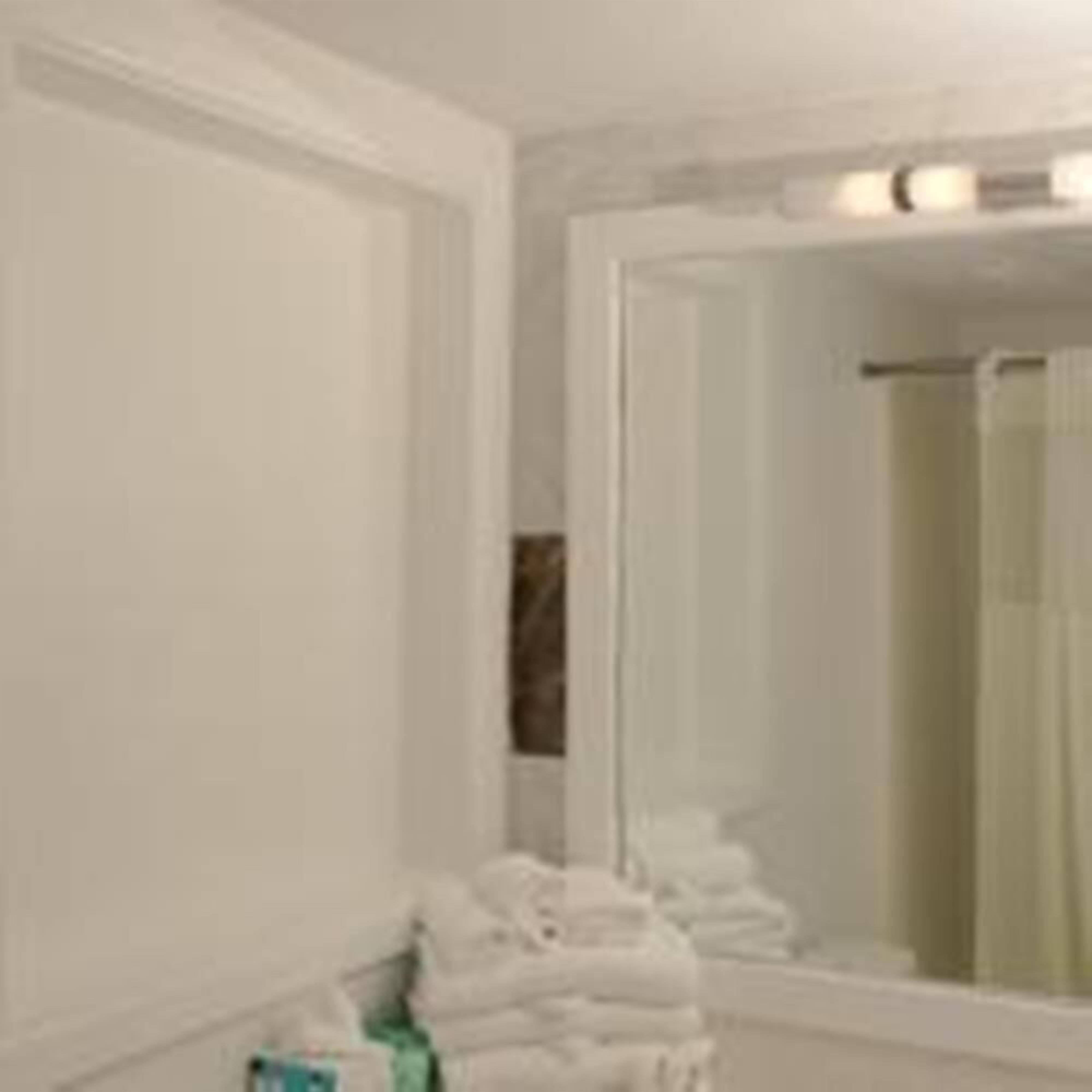 A bathroom with a large mirror, a towel rack, and a shower area.