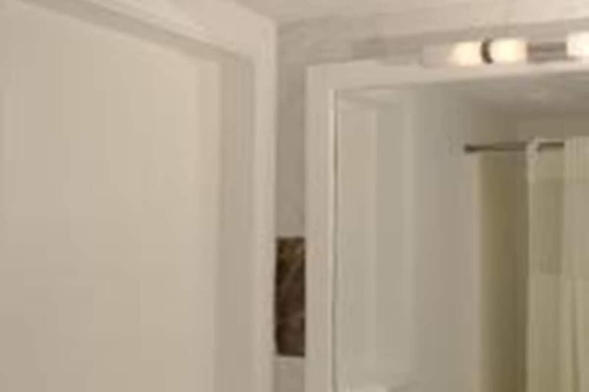 A bathroom with a large mirror, a towel rack, and a shower area.