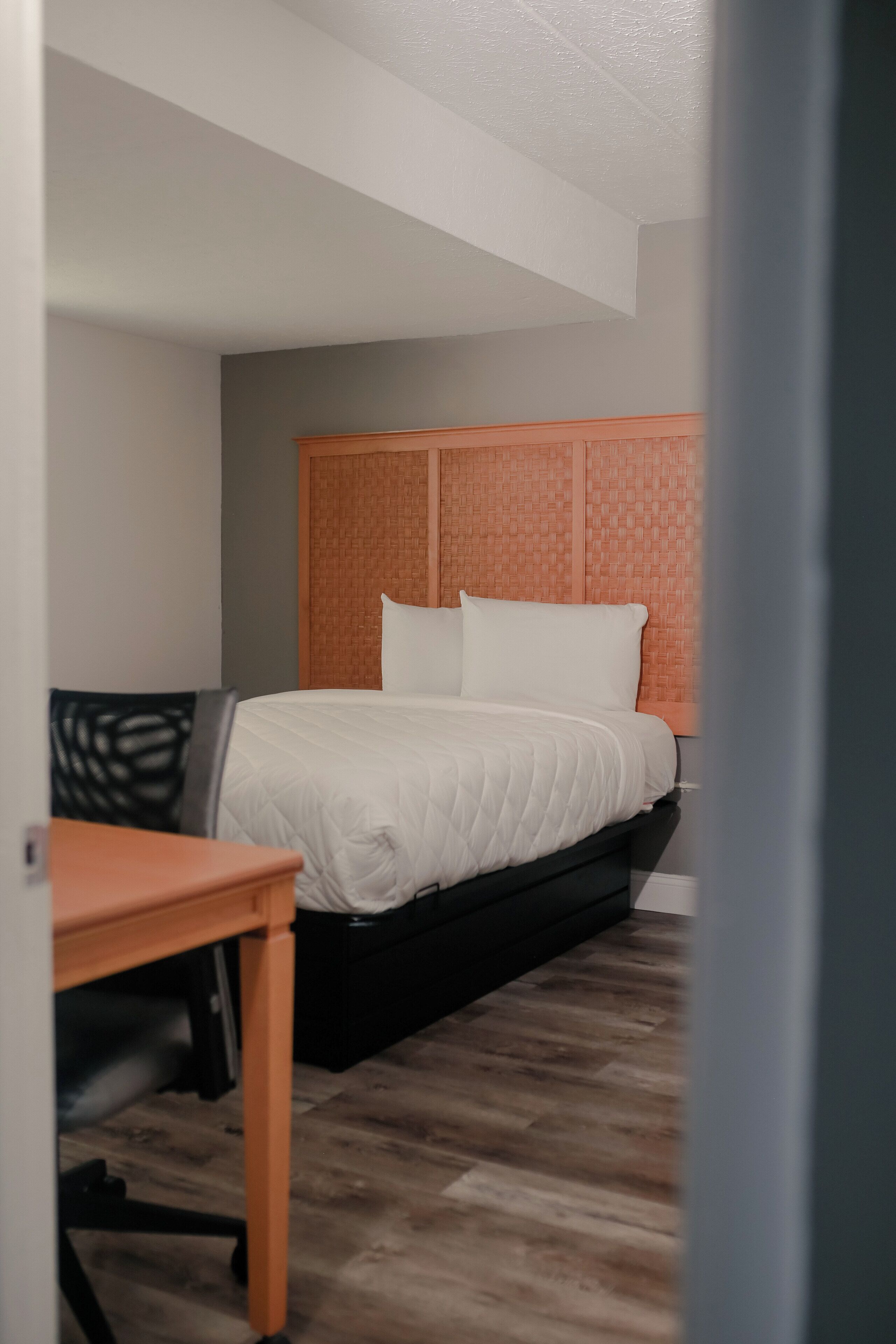 A hotel room with a bed, a desk, and a chair.