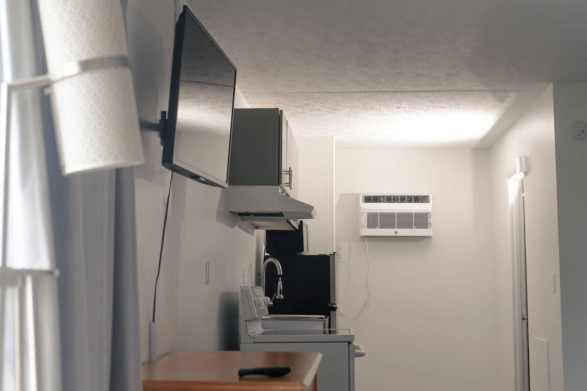 A compact kitchen with a wooden cabinet, a microwave, and a small refrigerator.