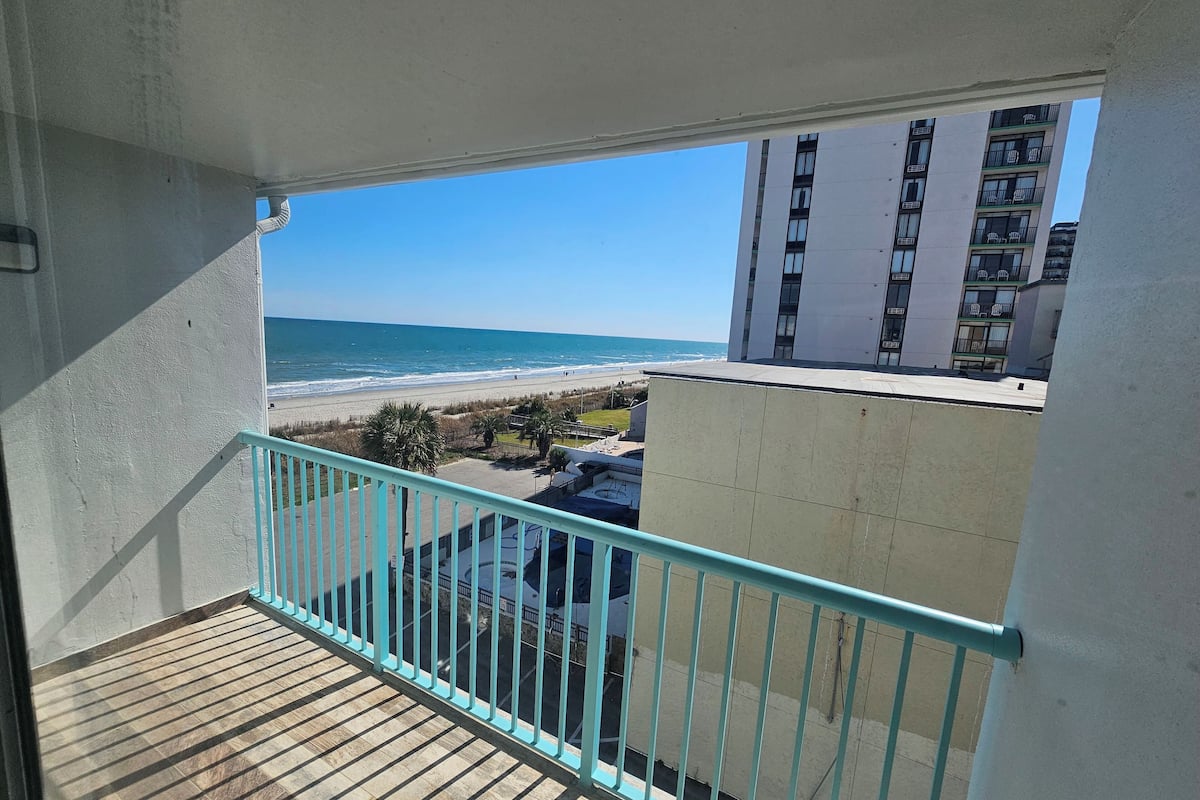 A balcony with a view of the beach and ocean.