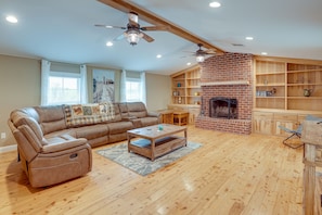 A spacious living room with a leather sofa, wooden coffee table, and a brick fireplace.