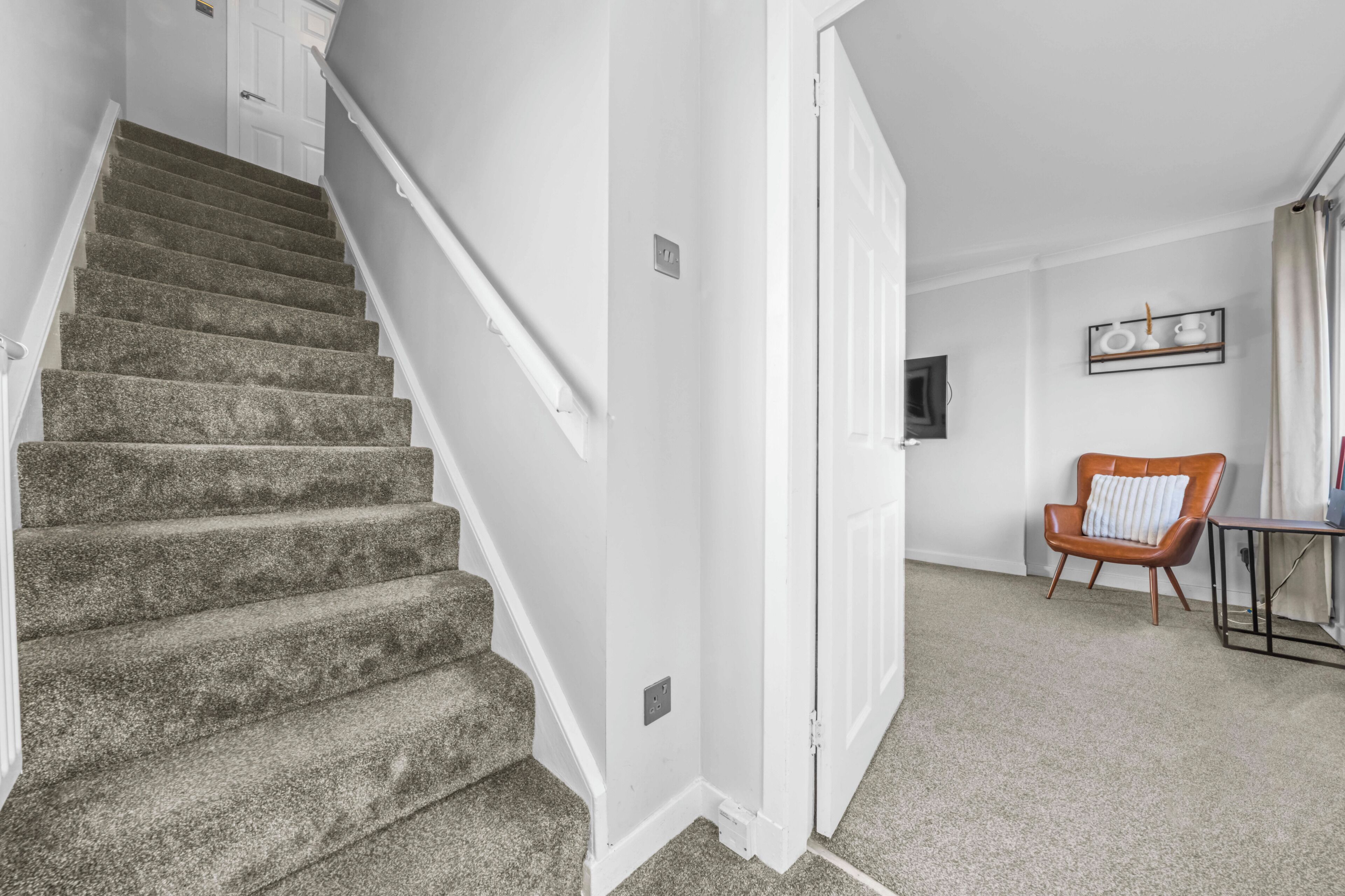 A staircase leading to a landing with a chair and a small table.