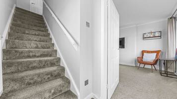 A staircase leading to a landing with a chair and a small table.