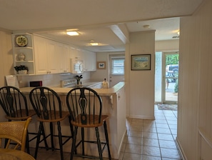 A kitchen with white cabinets, a stove, and a dining area with three chairs.