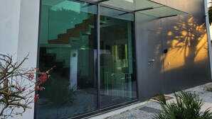 Ein modernes Gebäude mit großen Glasfenstern, einer sichtbaren Treppe und einem Kiesgrundstück.