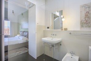A modern bathroom with a bed, a sink, a toilet, and a shower.