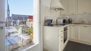 Una cocina con gabinetes blancos, una estufa, una cafetera y vistas a un edificio.