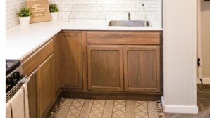 Een keuken met witte kasten, houten aanrechtblad en een varkzenkop aan de wand.