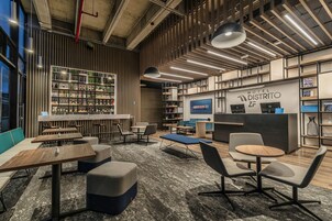 Un moderno vestíbulo de hotel con zona de bar, asientos y exhibición de servicios del hotel.