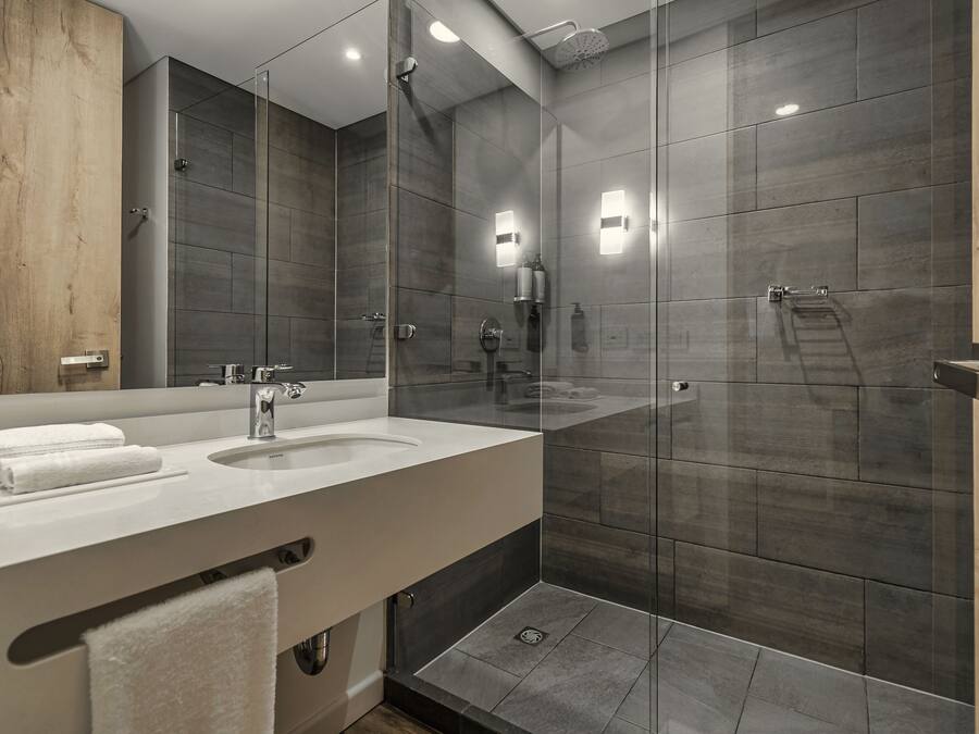 Une salle de bain moderne avec deux lavabos, une douche en verre et un grand miroir.