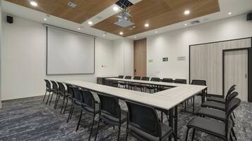 A conference room with a long table, chairs, a projector screen, and a whiteboard.