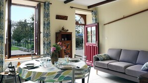 A dining area with a table set for four, a sofa, and a cabinet with decorative items.