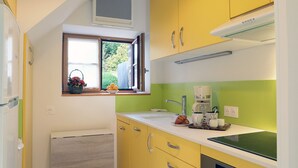 A compact kitchen with yellow cabinets, a window with a view, a coffee maker, and a toaster.