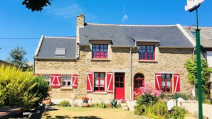 A stone building with red shutters and a sloped roof.