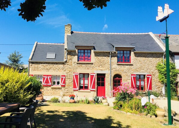 A stone building with red shutters and a sloped roof.