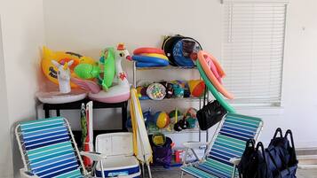 A room with two beach chairs, a cooler, and various children's toys and equipment.