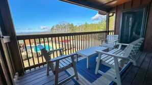 A covered outdoor area with a pool, lounge chairs, and a view of the surrounding landscape.