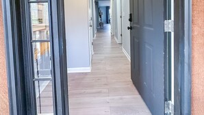 A hallway with a wooden floor, white walls, and a door on the right.