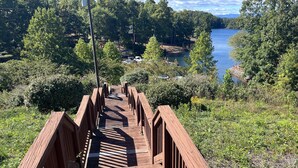 A wooden boardwalk leading to a lake with trees and a clear sky.