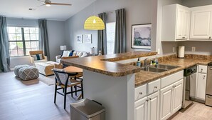 A modern kitchen with a central island, white cabinetry, and a ceiling fan.