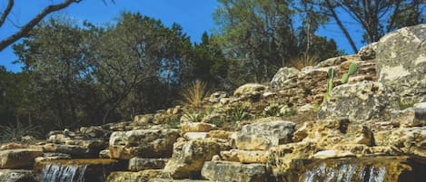 A natural landscape with a waterfall, rocky terrain, and trees.