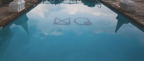 A clear blue pool with geometric shapes reflected on the water's surface.