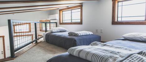 A bedroom with two beds, a window, and a view of a balcony.