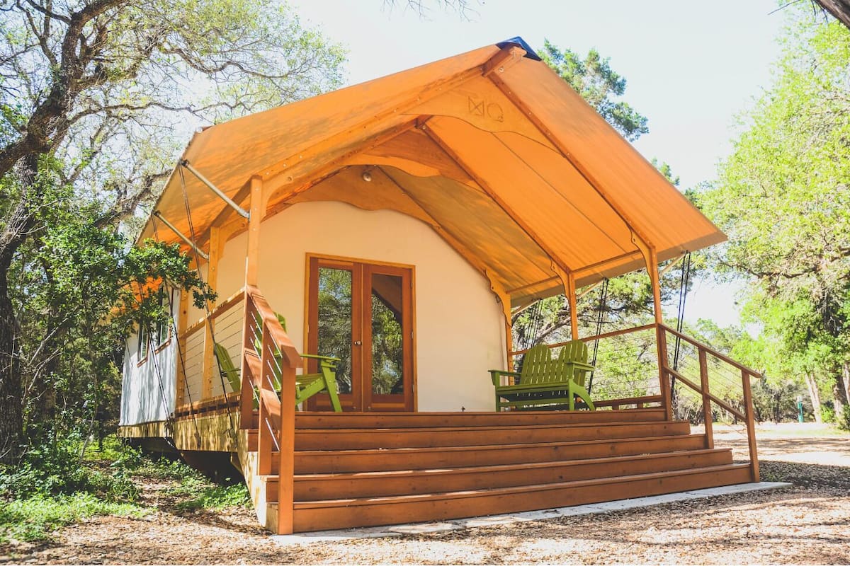 A wooden cabin with a porch, a door, and a staircase leading to the entrance.