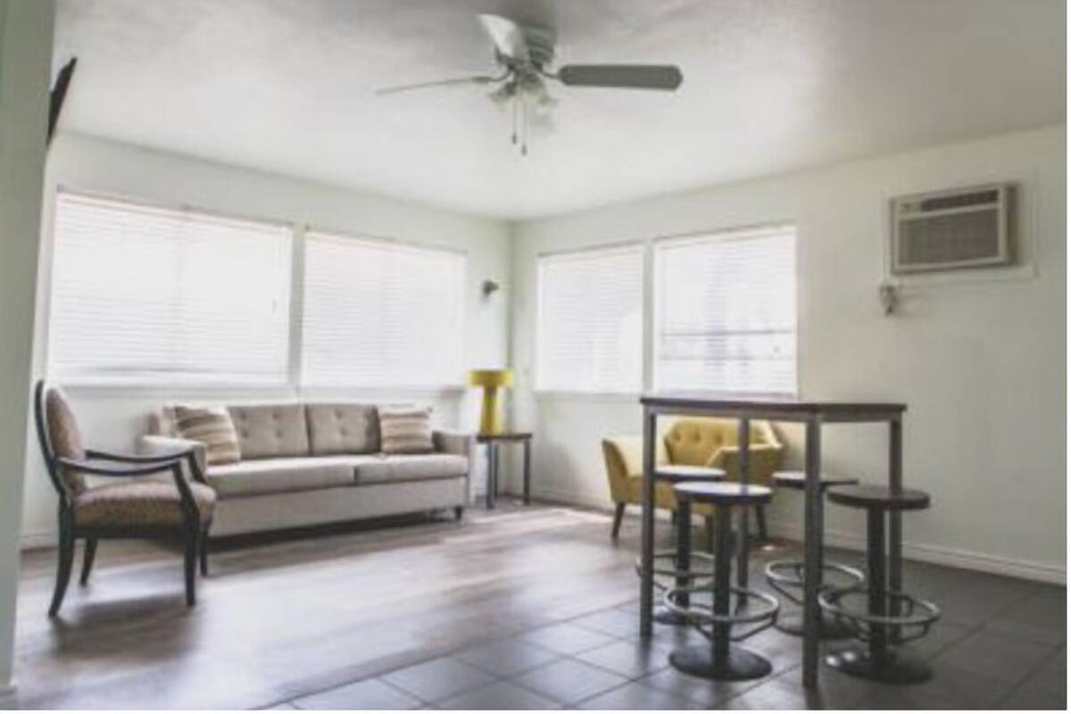 A living room with a sofa, chairs, a coffee table, and a ceiling fan.