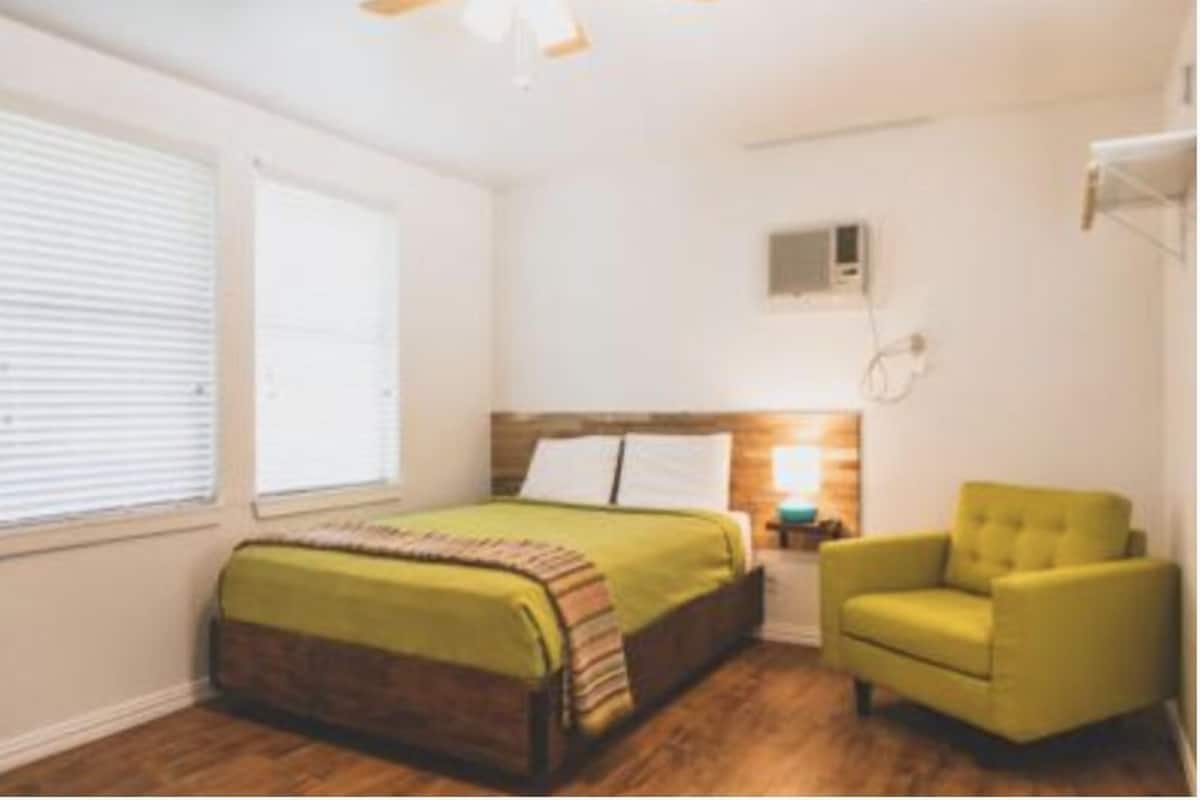 A bedroom with a bed, a chair, a nightstand, and a ceiling fan.