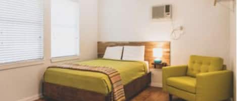 A bedroom with a bed, a chair, a nightstand, and a ceiling fan.