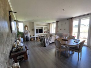 A modern kitchen with a dining area, large windows, and a flat-screen TV. - Warm & quiet country house (Cosnac)